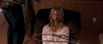 Movie still from “The Three Burials of Melquiades Estrada” (2005), directed by Tommy Lee Jones – A woman tied to a chair with tape over her mouth; Medium shot, High angle