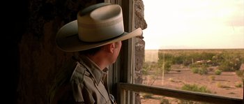 Movie still from “The Three Burials of Melquiades Estrada” (2005), directed by Tommy Lee Jones – A man wearing a cowboy hat looking out of a window; Close Up shot, Over the shoulder angle