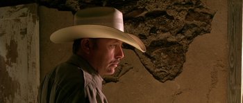 Movie still from “The Three Burials of Melquiades Estrada” (2005), directed by Tommy Lee Jones – A man wearing a cowboy hat in front of a stone wall; Close Up shot, Low angle
