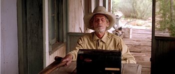 Movie still from “The Three Burials of Melquiades Estrada” (2005), directed by Tommy Lee Jones – An older man in a cowboy hat is holding a cigar; Medium shot, Low angle