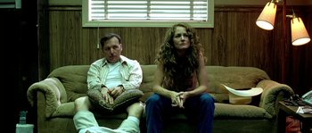 Movie still from “The Three Burials of Melquiades Estrada” (2005), directed by Tommy Lee Jones – A man and a woman sitting on a couch in a room; Medium shot, Low angle
