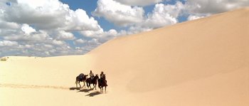 Movie still from “The Three Burials of Melquiades Estrada” (2005), directed by Tommy Lee Jones – A group of people riding horses in the desert; Extreme Wide shot, Low angle