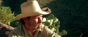 Movie still from “The Three Burials of Melquiades Estrada” (2005), directed by Tommy Lee Jones – An older man wearing a cowboy hat with a cactus in the background; Close Up shot, Low angle