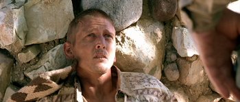 Movie still from “The Three Burials of Melquiades Estrada” (2005), directed by Tommy Lee Jones – A man with a shaved head is standing in front of a rock wall; Close Up shot, High angle