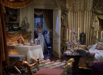 Movie still from “The Three Musketeers” (1948), directed by George Sidney – A woman standing in front of a dining room table; Wide shot, High angle
