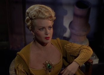 Movie still from “The Three Musketeers” (1948), directed by George Sidney – A woman with blonde hair and a green brooch in a yellow dress; Close Up shot, Over the shoulder angle