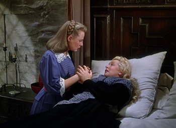Movie still from “The Three Musketeers” (1948), directed by George Sidney – A woman is holding her hand out to another woman in a bed; Medium shot, High angle