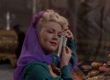 Movie still from “The Three Musketeers” (1948), directed by George Sidney – A woman with a purple head scarf holding a cell phone to her ear; Close Up shot, Low angle