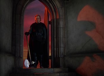 Movie still from “The Three Musketeers” (1948), directed by George Sidney – A man standing in front of an arched doorway holding an axe; Wide shot, Low angle