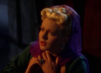 Movie still from “The Three Musketeers” (1948), directed by George Sidney – A woman with blonde hair wearing a green dress and a purple scarf; Close Up shot, High angle