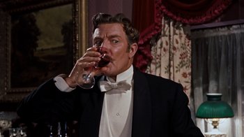 Movie still from “The Time Machine” (1960), directed by George Pal – A man in a tuxedo drinking a glass of red wine; Medium shot, Low angle