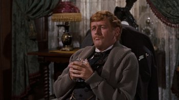 Movie still from “The Time Machine” (1960), directed by George Pal – A man sitting in a chair holding a glass of beer; Medium shot, High angle