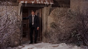 Movie still from “The Time Machine” (1960), directed by George Pal – A man in a suit and tie standing in front of a building; Medium shot, Low angle