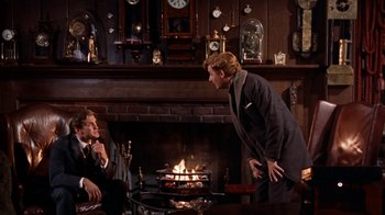 Movie still from “The Time Machine” (1960), directed by George Pal – Two men in suits are talking in front of a fire place; Medium shot, Over the shoulder angle