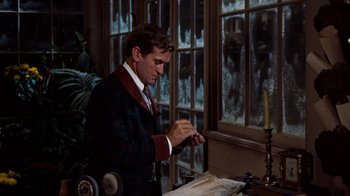 Movie still from “The Time Machine” (1960), directed by George Pal – A man standing in front of a window with a candle; Medium shot, Over the shoulder angle