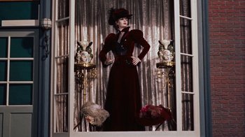 Movie still from “The Time Machine” (1960), directed by George Pal – A woman in a long red dress and a hat; Medium shot, Low angle