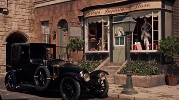 Movie still from “The Time Machine” (1960), directed by George Pal – An antique car parked on the side of the street; Wide shot, High angle