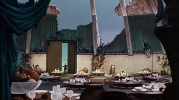Movie still from “The Time Machine” (1960), directed by George Pal – An empty room with a lot of plates on the table; Extreme Wide shot, High angle