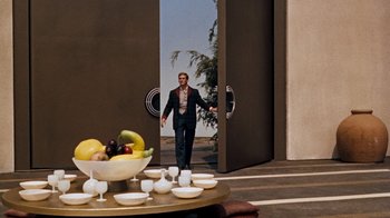 Movie still from “The Time Machine” (1960), directed by George Pal – A man standing in front of a table with a bowl of fruit on top of it; Wide shot, Over the shoulder angle