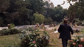 Movie still from “The Time Machine” (1960), directed by George Pal – A group of people sitting in the grass near a body of water; Extreme Wide shot, Over the shoulder angle