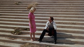 Movie still from “The Time Machine” (1960), directed by George Pal – A man and a woman sitting on some steps; Wide shot, High angle