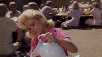 Movie still from “The Time Machine” (1960), directed by George Pal – A woman in a pink shirt is holding a white pitcher; Medium shot, Low angle