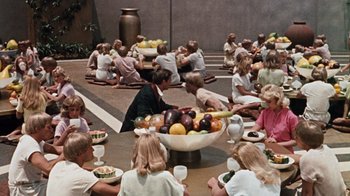 Movie still from “The Time Machine” (1960), directed by George Pal – A group of people sitting around a bowl of fruit; Wide shot, High angle