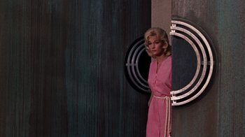 Movie still from “The Time Machine” (1960), directed by George Pal – A woman in a pink dress standing next to a wall; Medium shot, Low angle