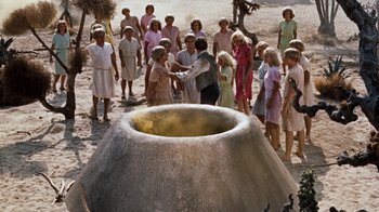 Movie still from “The Time Machine” (1960), directed by George Pal – A group of people standing around a large pot; Wide shot, High angle