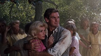 Movie still from “The Time Machine” (1960), directed by George Pal – A man and a woman embracing each other in front of a tree; Close Up shot, Low angle