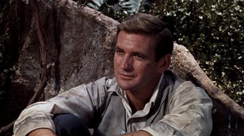 Movie still from “The Time Machine” (1960), directed by George Pal – A person sitting on the ground near a rock; Close Up shot, Low angle
