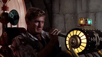Movie still from “The Time Machine” (1960), directed by George Pal – A man holding an object in front of an electric fan; Medium shot, Low angle