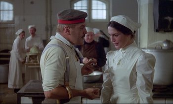 Movie still from “The Tin Drum” (1979), directed by Volker Schlöndorff – A man and a woman in white uniforms in a kitchen; Medium shot, Over the shoulder angle