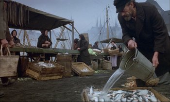Movie still from “The Tin Drum” (1979), directed by Volker Schlöndorff – A group of people standing around a fish market; Wide shot, High angle