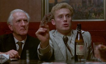 Movie still from “The Tin Drum” (1979), directed by Volker Schlöndorff – A man sitting in front of a bottle of beer; Close Up shot, Over the shoulder angle