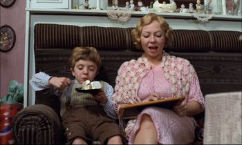 Movie still from “The Tin Drum” (1979), directed by Volker Schlöndorff – A woman and a boy sitting on a couch; Medium shot, High angle