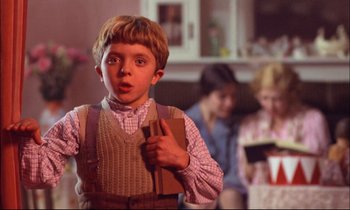 Movie still from “The Tin Drum” (1979), directed by Volker Schlöndorff – A young boy holding a book in his hand; Medium shot, Over the shoulder angle
