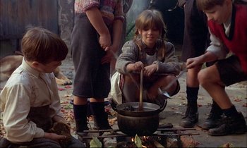 Movie still from “The Tin Drum” (1979), directed by Volker Schlöndorff – A group of people gathered around a pot on a fire; Medium shot, High angle