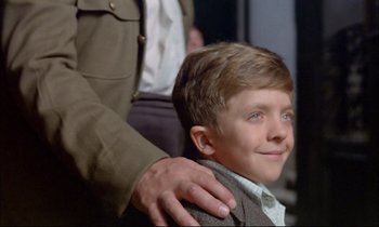 Movie still from “The Tin Drum” (1979), directed by Volker Schlöndorff – A young boy is being fitted for a suit; Close Up shot, Over the shoulder angle