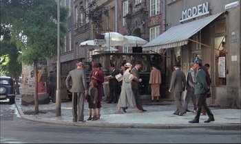Movie still from “The Tin Drum” (1979), directed by Volker Schlöndorff – A group of people standing on the side of the street; Wide shot, High angle
