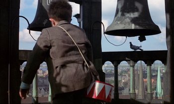 Movie still from “The Tin Drum” (1979), directed by Volker Schlöndorff – A boy is standing in a tower looking at the sky; Wide shot, Low angle