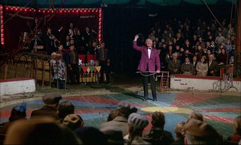 Movie still from “The Tin Drum” (1979), directed by Volker Schlöndorff – A man in a purple suit is on a circus ring; Wide shot, High angle
