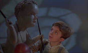 Movie still from “The Tin Drum” (1979), directed by Volker Schlöndorff – A young boy looking at a statue of a head; Medium shot, Low angle