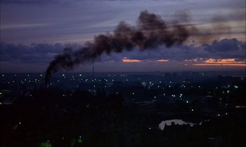 Movie still from “The Tin Drum” (1979), directed by Volker Schlöndorff – A view of a city at night with smoke billowing out of it; Extreme Wide shot, High angle