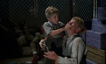 Movie still from “The Tin Drum” (1979), directed by Volker Schlöndorff – A young boy is helping a younger man shave his face; Medium shot, Over the shoulder angle