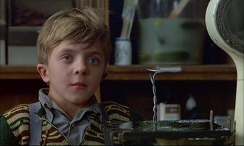 Movie still from “The Tin Drum” (1979), directed by Volker Schlöndorff – A young boy sitting in front of a fish tank; Close Up shot, Low angle