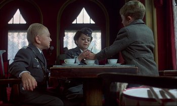 Movie still from “The Tin Drum” (1979), directed by Volker Schlöndorff – A group of people sitting at a table with cups; Medium shot, Over the shoulder angle