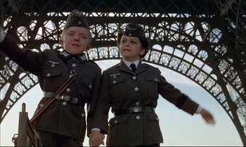 Movie still from “The Tin Drum” (1979), directed by Volker Schlöndorff – A couple of people that are standing in front of a bridge; Medium shot, Low angle