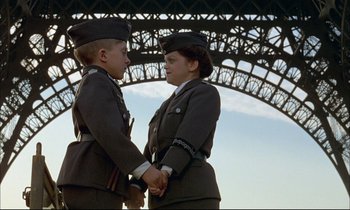 Movie still from “The Tin Drum” (1979), directed by Volker Schlöndorff – A woman and a young boy holding hands under an iron bridge; Medium shot, Low angle