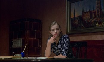 Movie still from “The Tin Drum” (1979), directed by Volker Schlöndorff – A woman sitting at a table in front of a painting; Medium shot, Over the shoulder angle